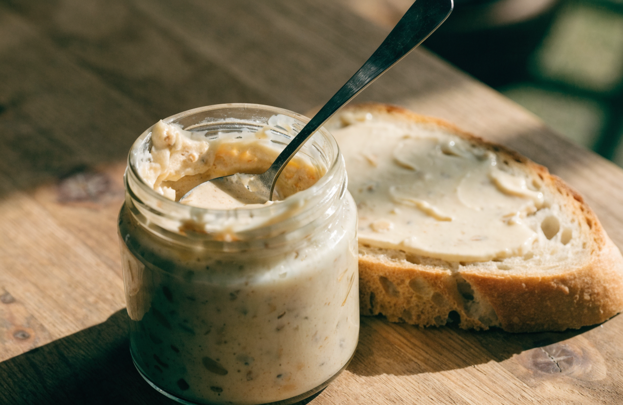A jar of creamy maple butter spread on rustic bread
